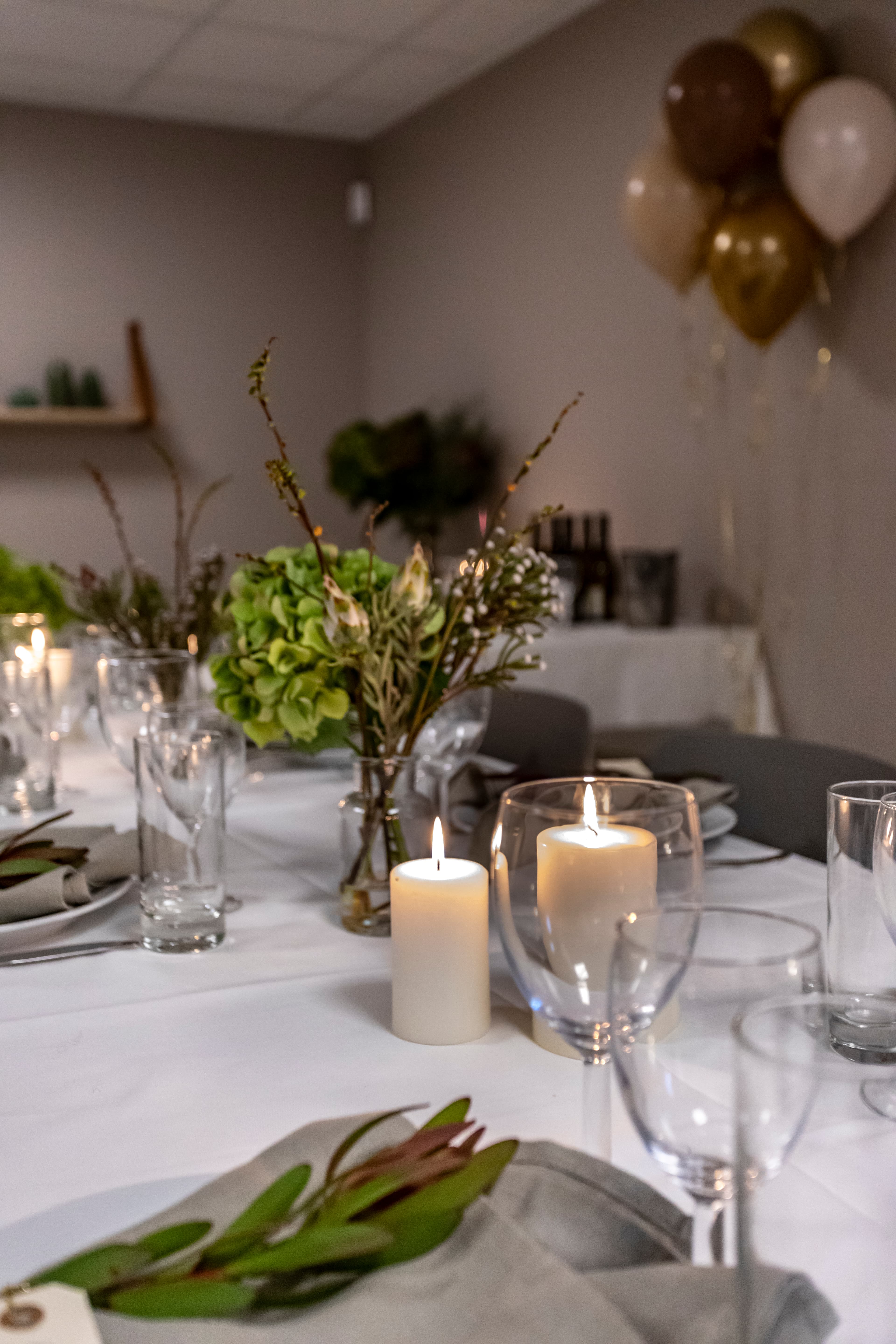 A long dining table set for guests, with balloons in the background