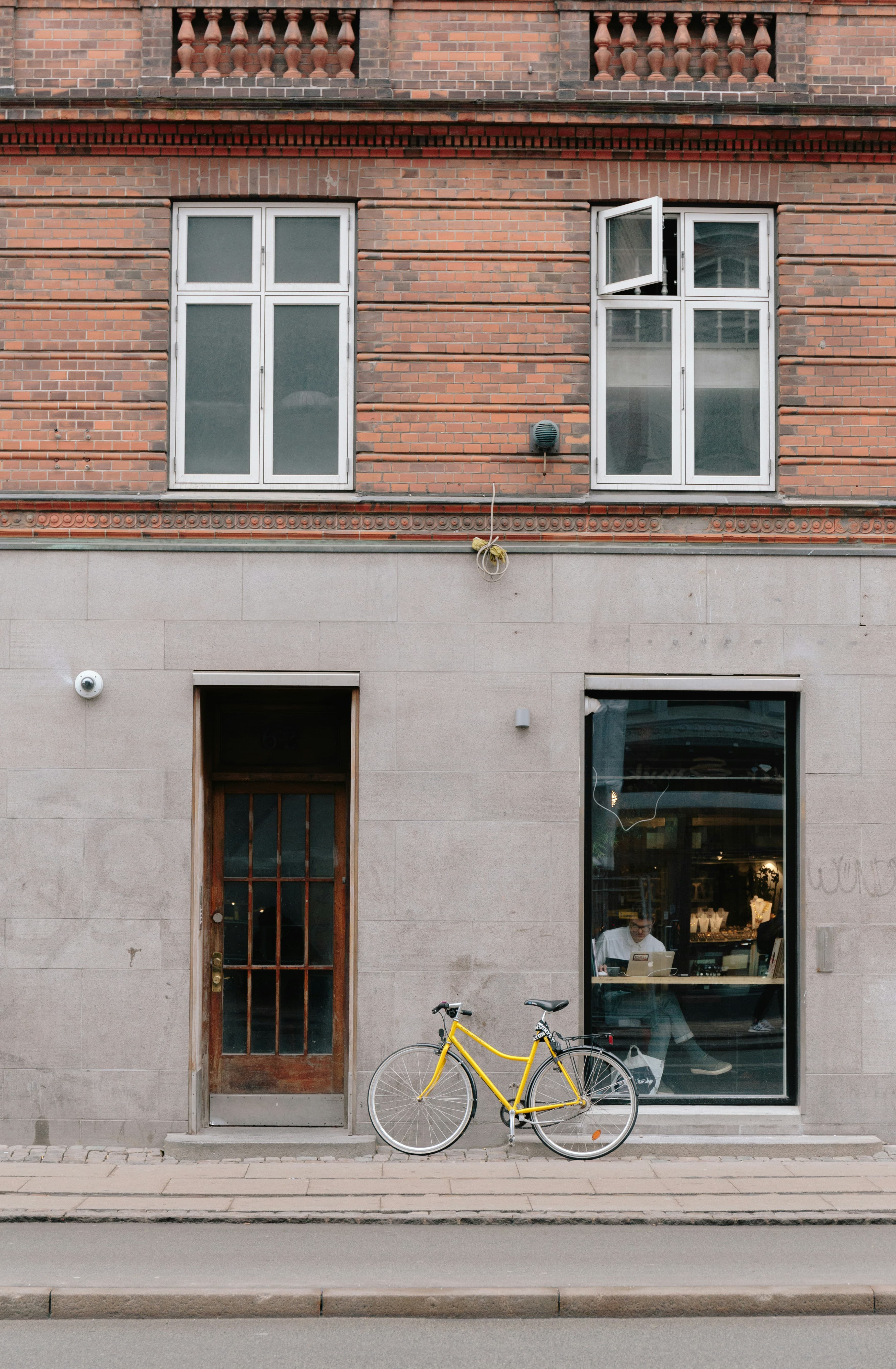 A man sitting by the window in a café, with a bicycle leaning against the façade