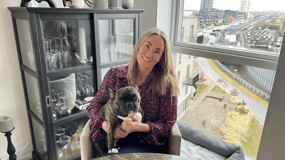 Anja sits with her dog Alfred in the living room of their flat at Øresund Park.