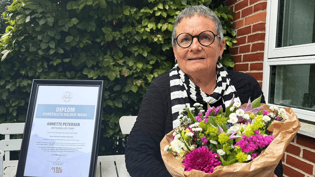 Annette, beboer på ejendommen Østerfælled Torv, på sin terrasse på sin med blomster og diplom