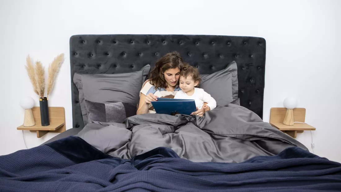 Mor og datter læser bog i sengen